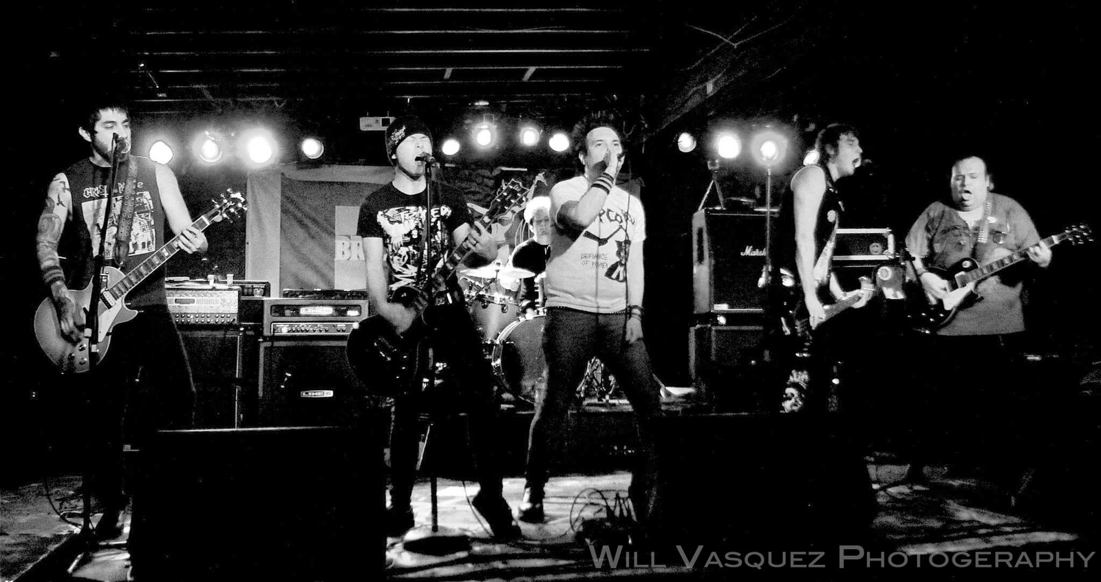 Guitarist on stage under blue and magenta lights at a club show