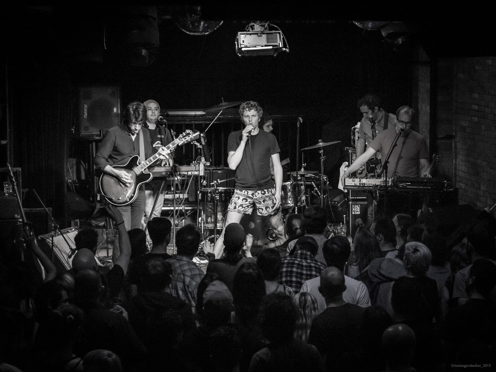 Black-and-white photo of a punk band playing to an intimate crowd